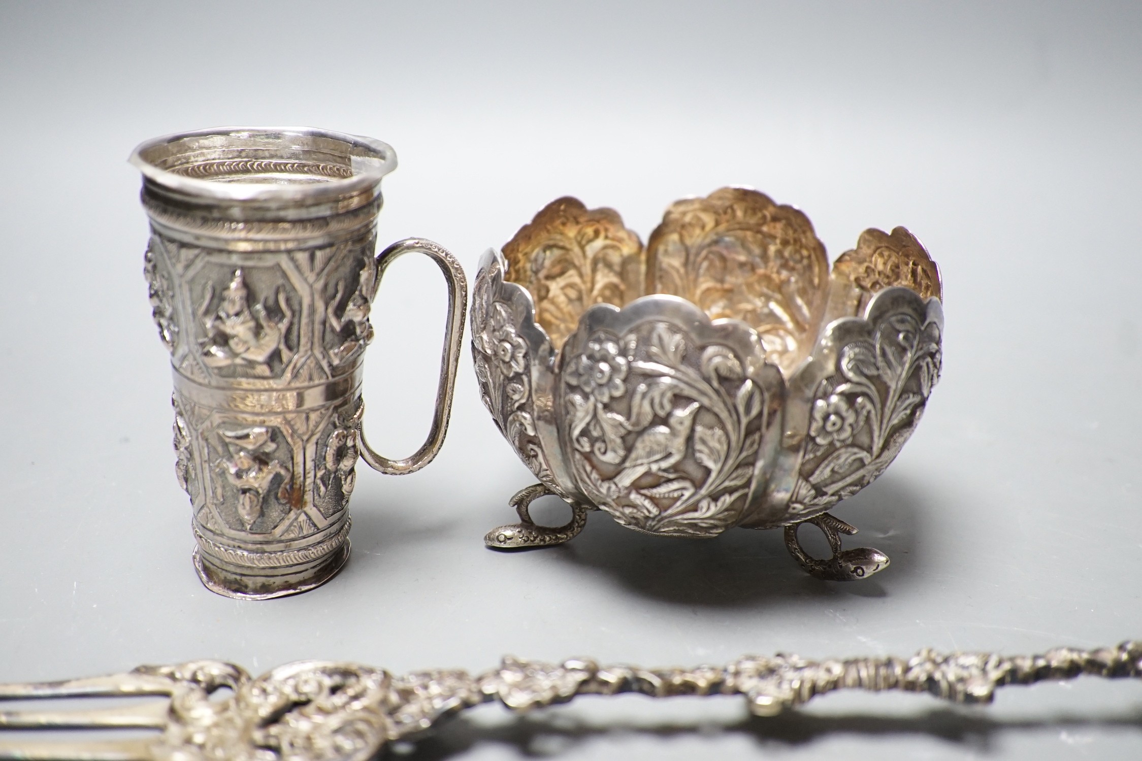 A Dutch white metal toasting fork, with pepperette? finial modelled as a bird, 28.5cm, an Indian white metal double measure cup and a similar bowl.